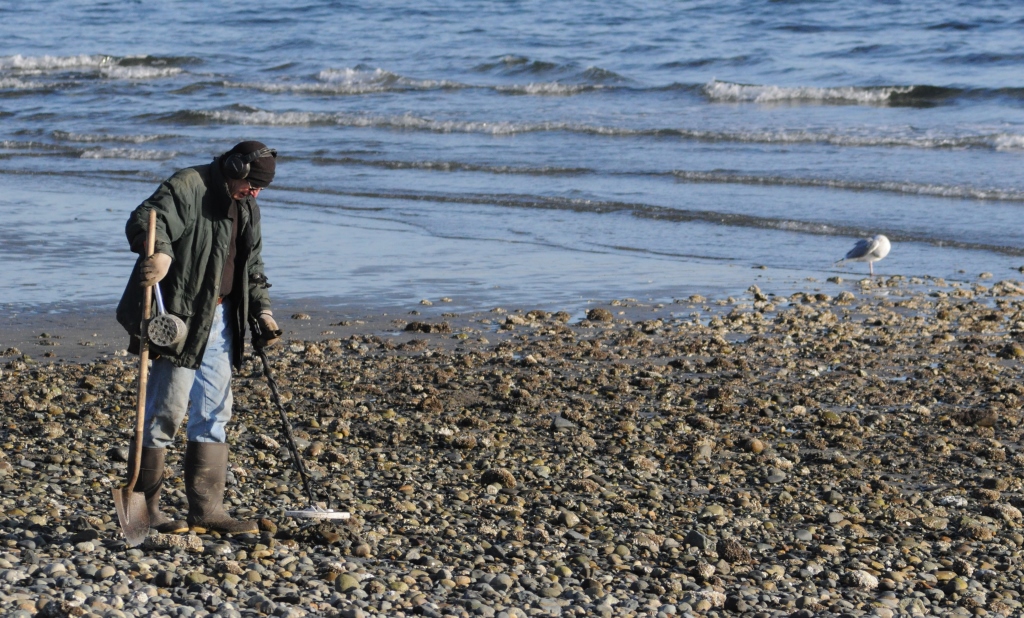 man using metal detector on beach 2